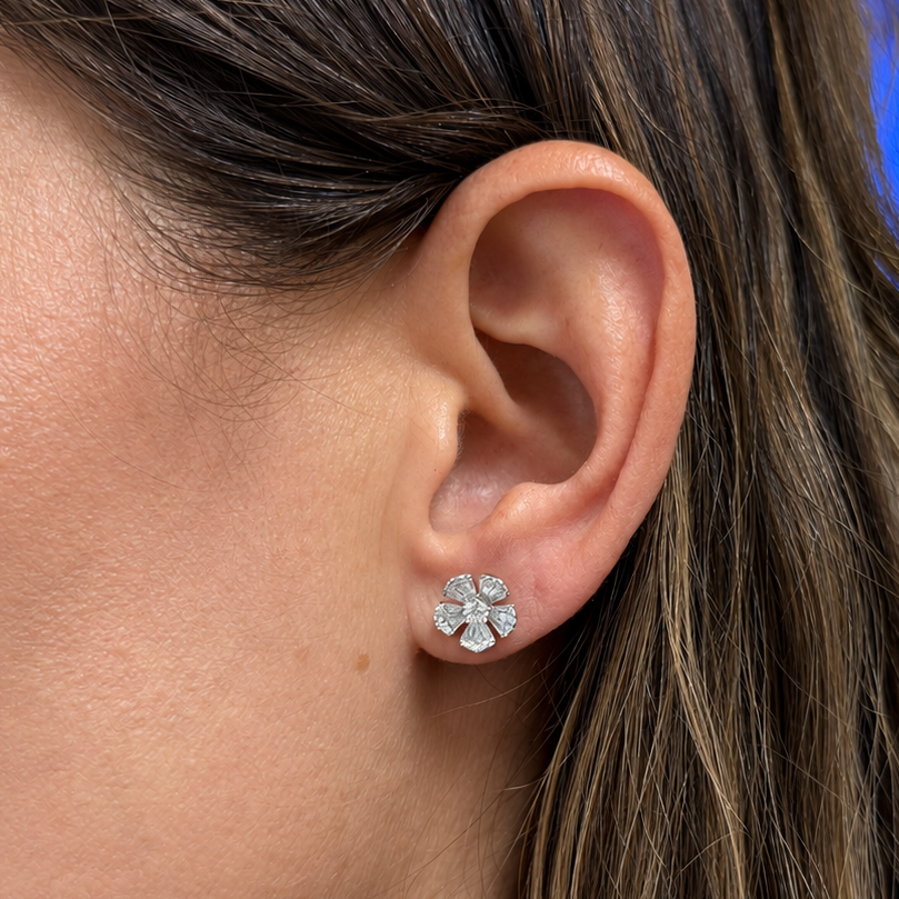 Detail of baguette and round diamonds set across the five petals of an 18k gold stud