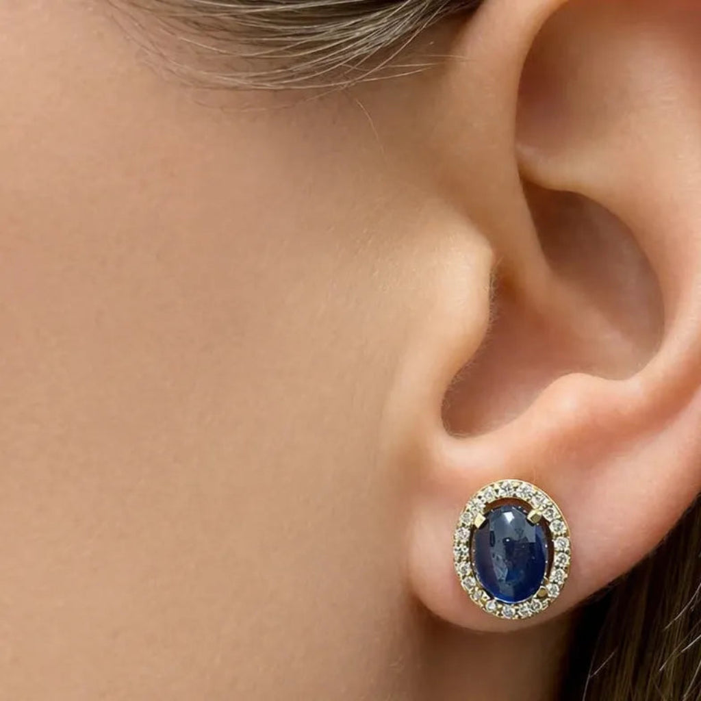18k yellow gold stud earrings featuring oval sapphire cabochons framed by diamond halos