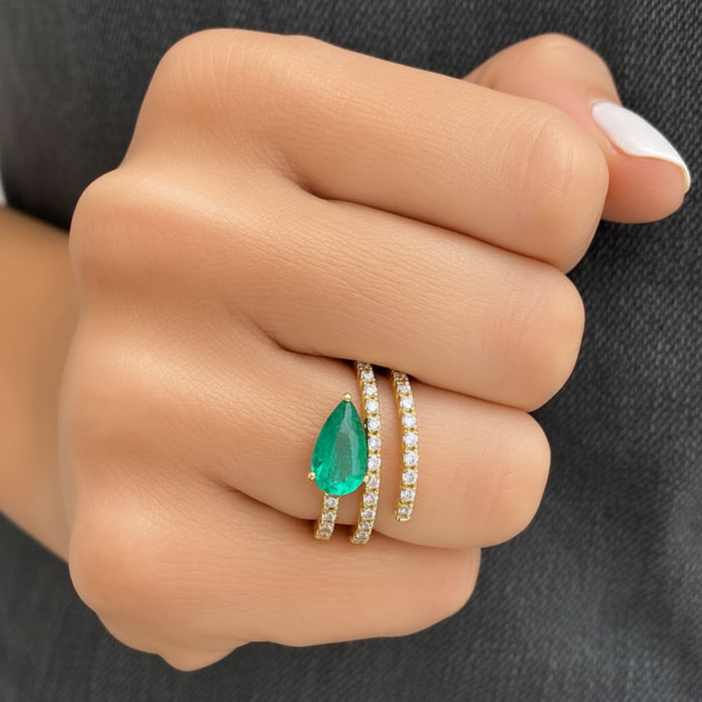 18k gold ring with a pear-shaped emerald surrounded by round diamonds