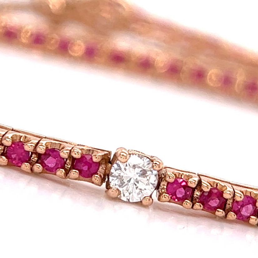 18k yellow gold tennis bracelet with red ruby links and a central diamond detail
