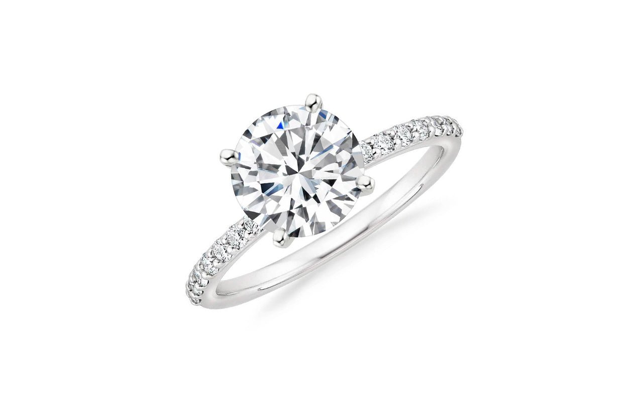 Round brilliant diamond engagement ring with pavé band, symbolizing timeless elegance by Diamond Tales