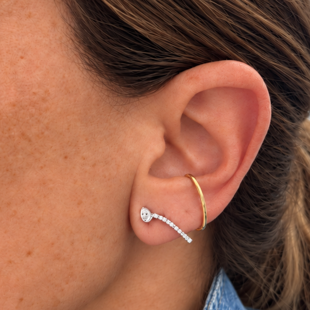 Detail of 15 round diamonds set in white gold on an 18k yellow gold ear climber