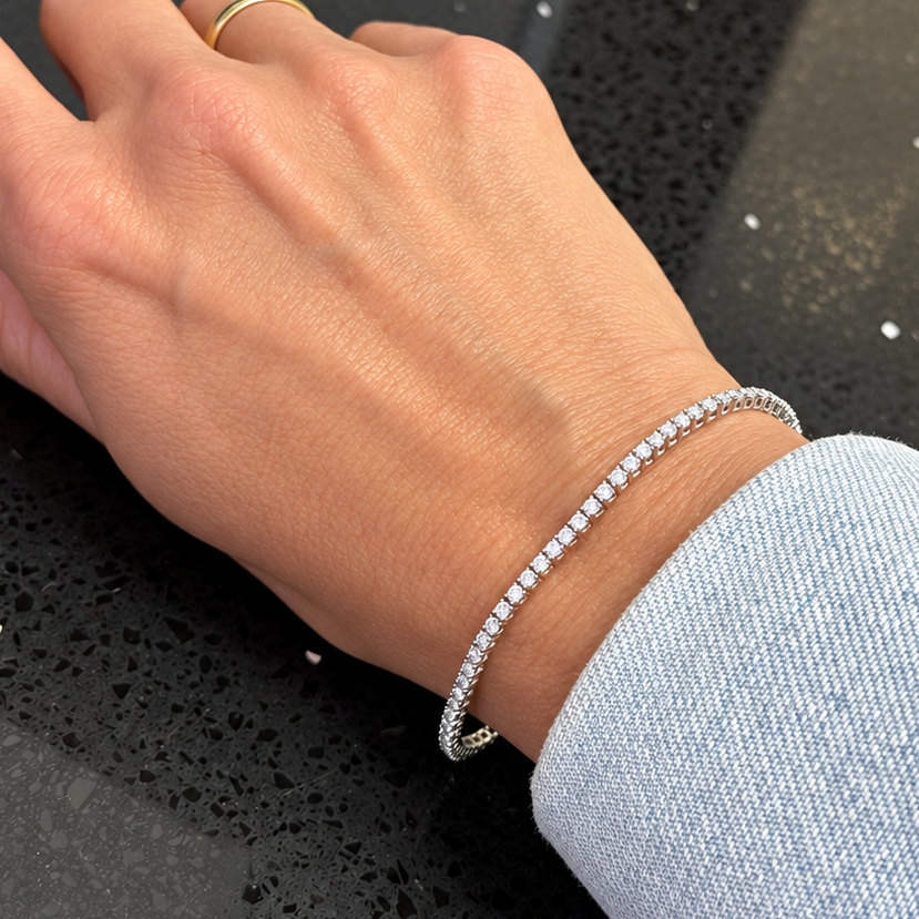 Close-up of matched round brilliant diamonds along an 18k white gold tennis bracelet