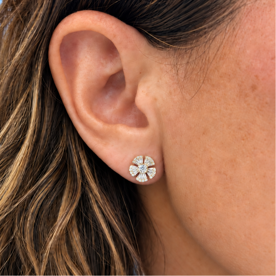 Detail of baguette and round diamonds across the petals of an 18k yellow gold stud