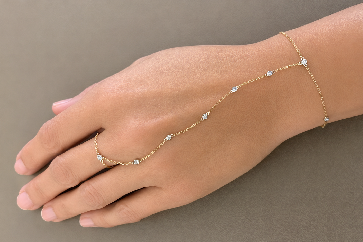 bezel set diamond hand chain bracelet in 14k gold, worn on the hand