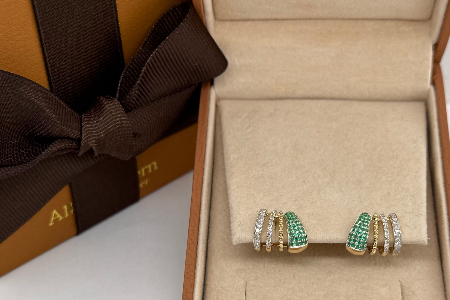 emerald and diamond stud earrings on the ear, close up