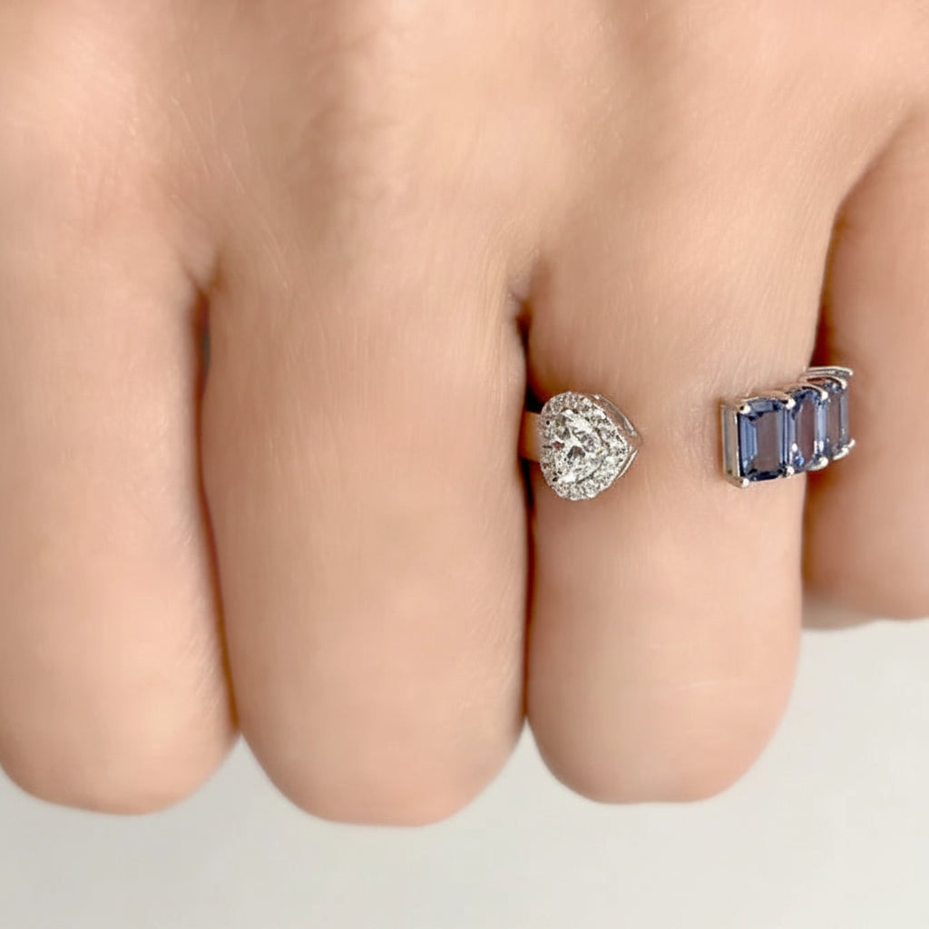 18k white gold open band ring with four emerald-cut blue sapphires and a diamond heart motif