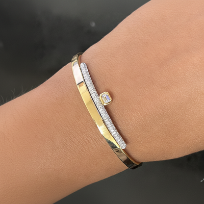 Emerald cut and round diamond bangle bracelet shown worn on the wrist