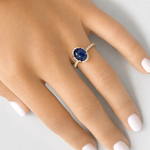18k yellow gold ring featuring an oval blue sapphire cabochon surrounded by a diamond halo
