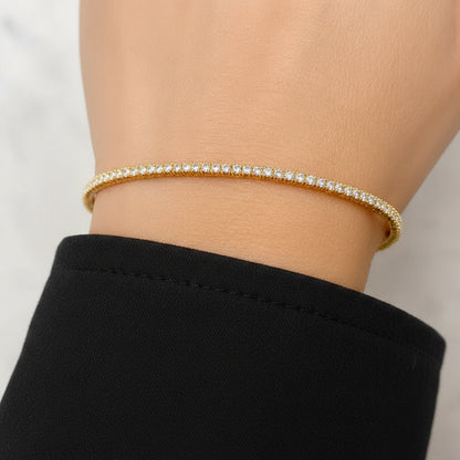 rigid 14k yellow gold tennis bangle bracelet with round diamonds encircling the band