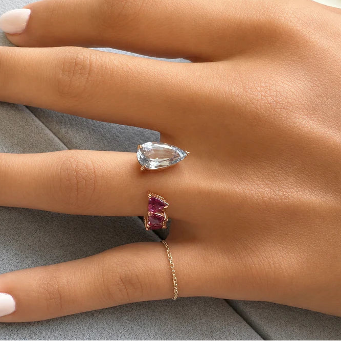 18k gold ring with pear sapphire and trillion-cut rubellite in a bypass design